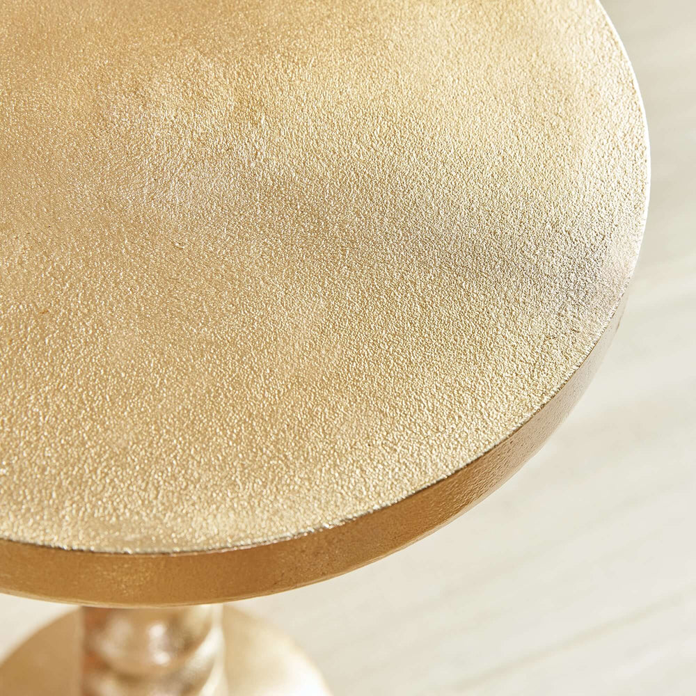 Close-up of vintage gold accent table top with textured finish and elegant design.