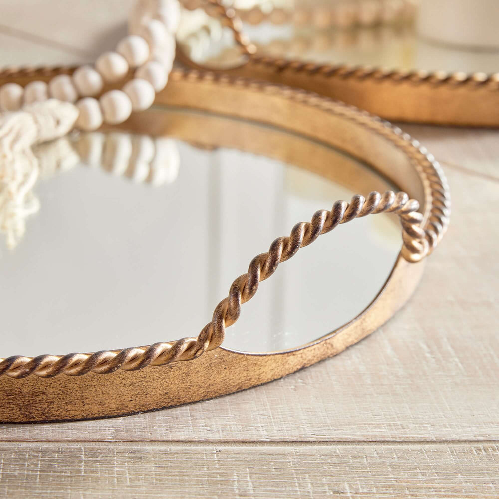 Vintage gold mirrored tray with braided handles, reflecting light for elegant décor.