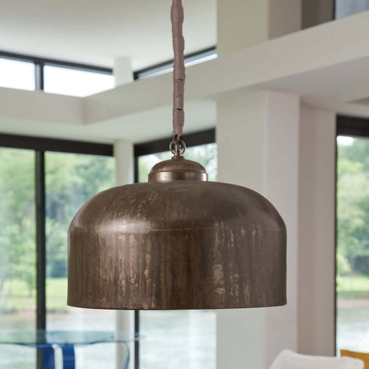 Vintage industrial iron pendant light with jute wrap in modern home setting, showcasing rustic charm and artisanal design.