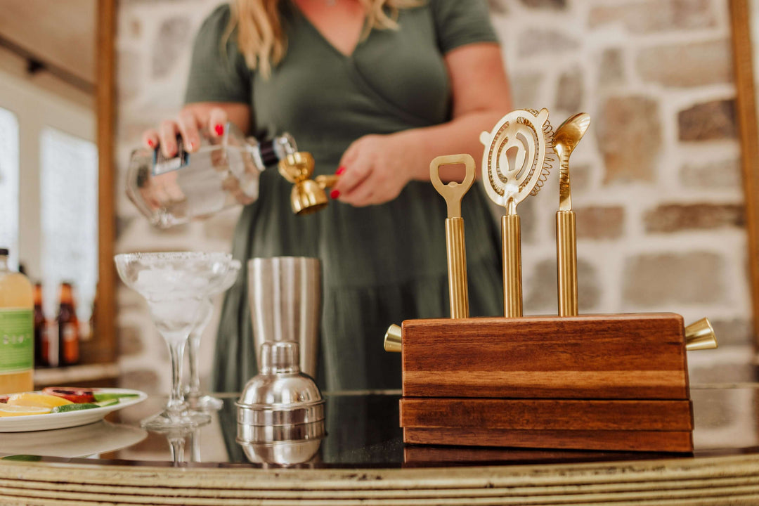 Vintage-Inspired Bar Tool Set with Brass Finish on bar counter with a person preparing a cocktail in the background