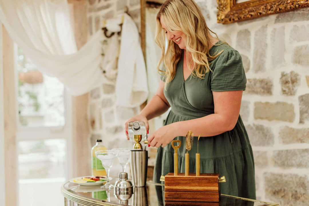 Woman preparing drinks with Vintage-Inspired Bar Tool Set with Brass Finish on a stylish bar table.