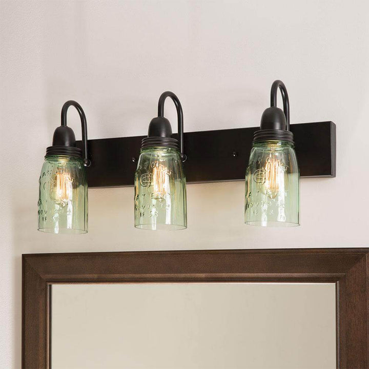 Vintage Mason Jar wall-mounted vanity light fixture with three glass shades and black metal base.