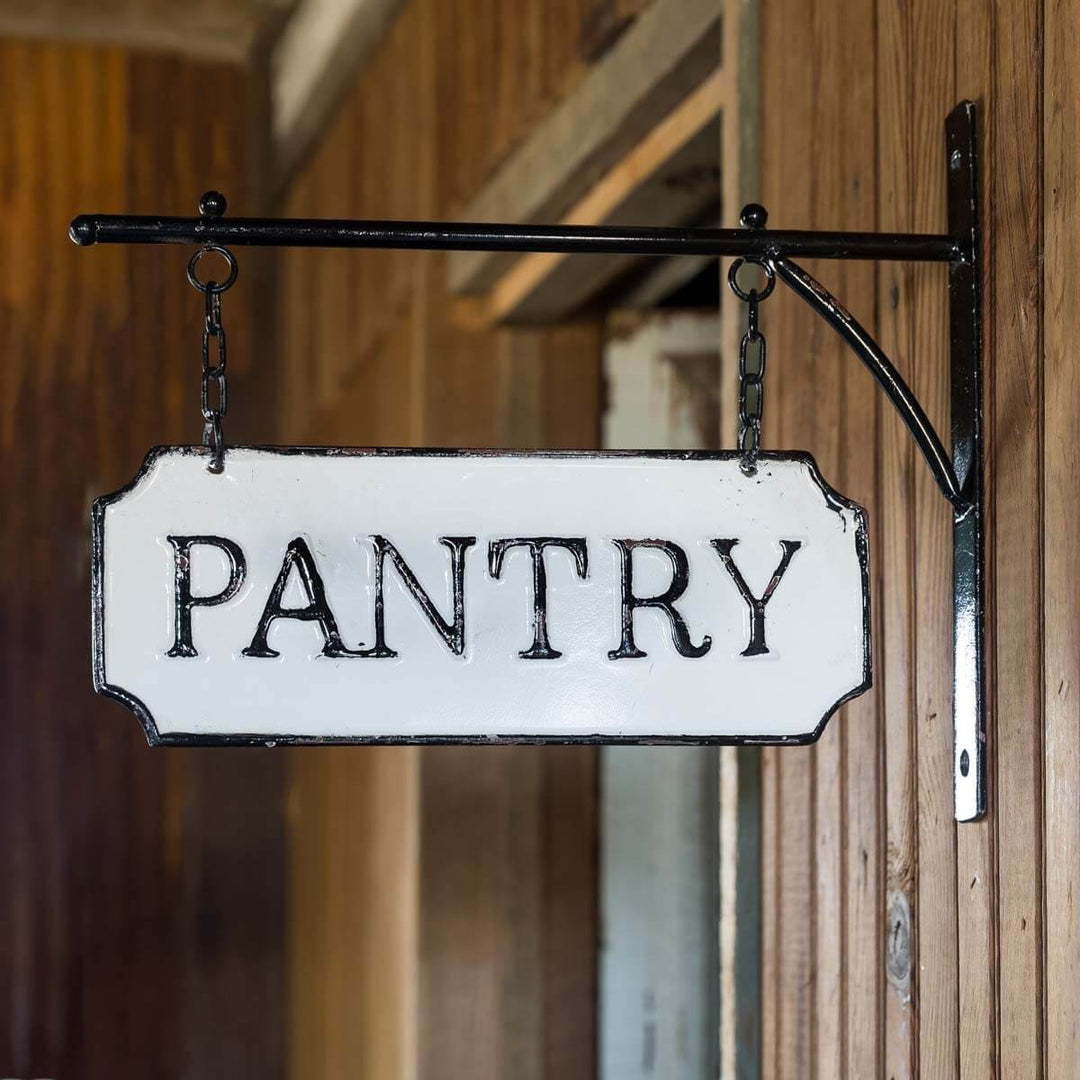 Vintage metal pantry sign with hanging display bar in black-and-white enamel finish, adding a nostalgic country kitchen charm.