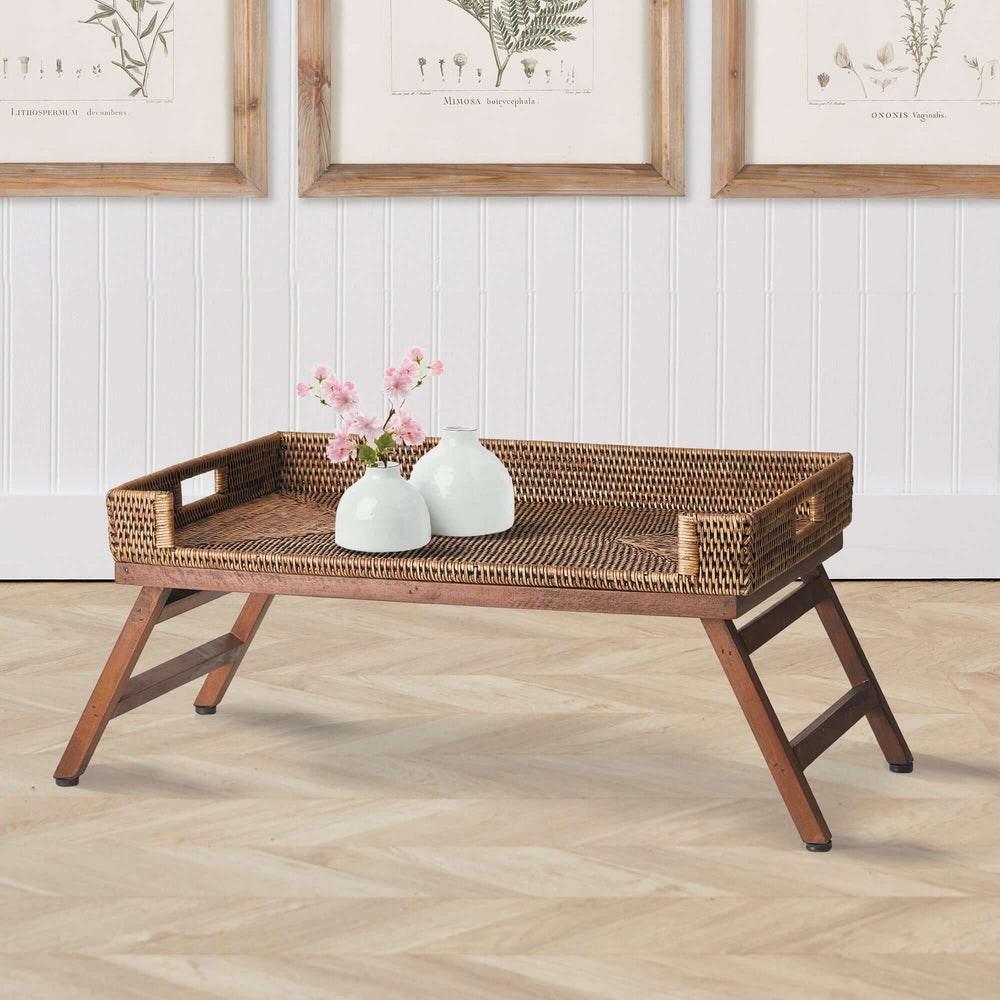 Vintage rattan tray table with collapsible legs, adorned with flowers and vases, perfect for elegant home decor.