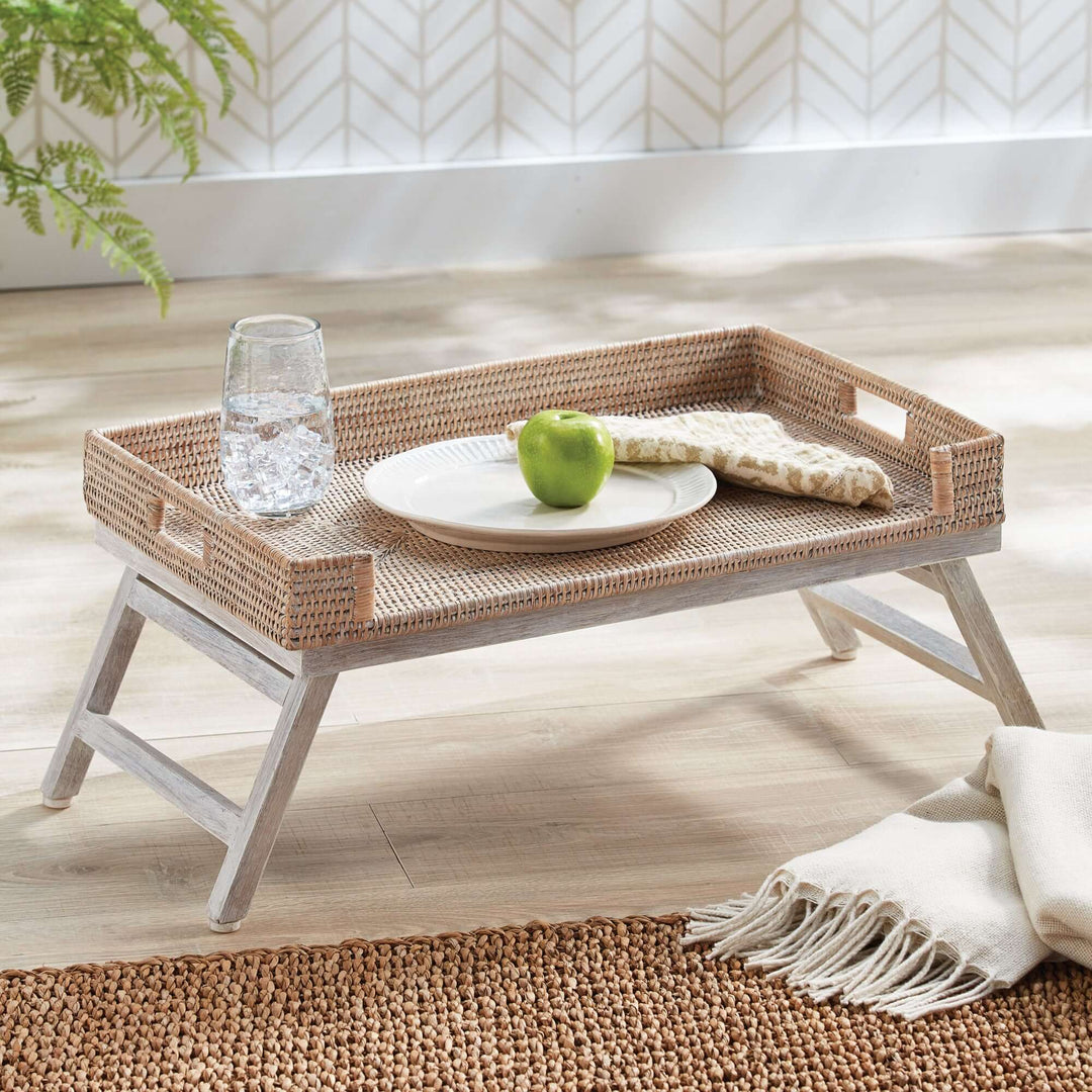 Vintage rattan tray table with collapsible legs, featuring a plate, green apple, and a glass of water.