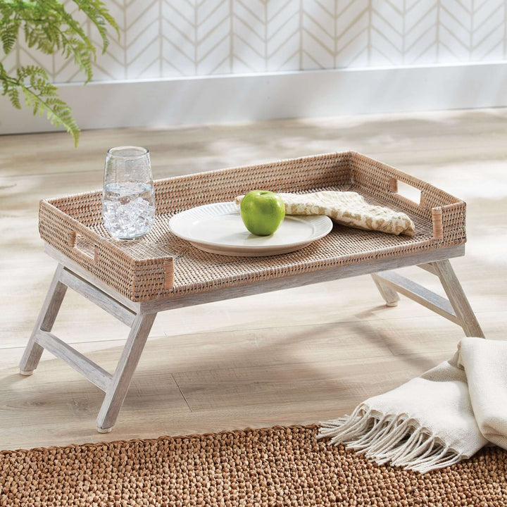 Vintage rattan tray table with collapsible legs, featuring a plate, green apple, and a glass of water.
