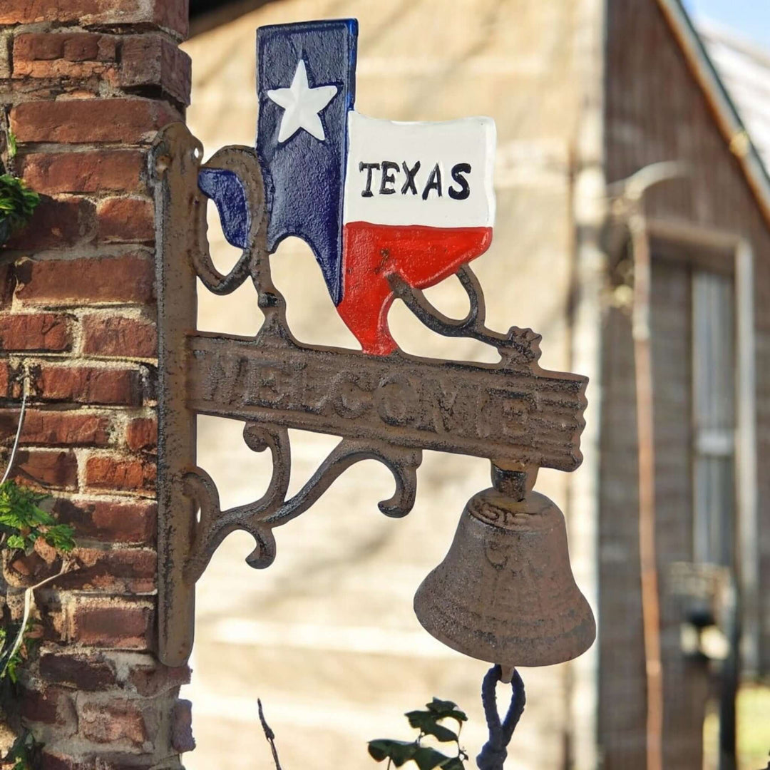 Vintage Texas Cast Iron Welcome Bell mounted on a rustic wall, featuring state-shaped silhouette and Lone Star colors, outdoor decor.