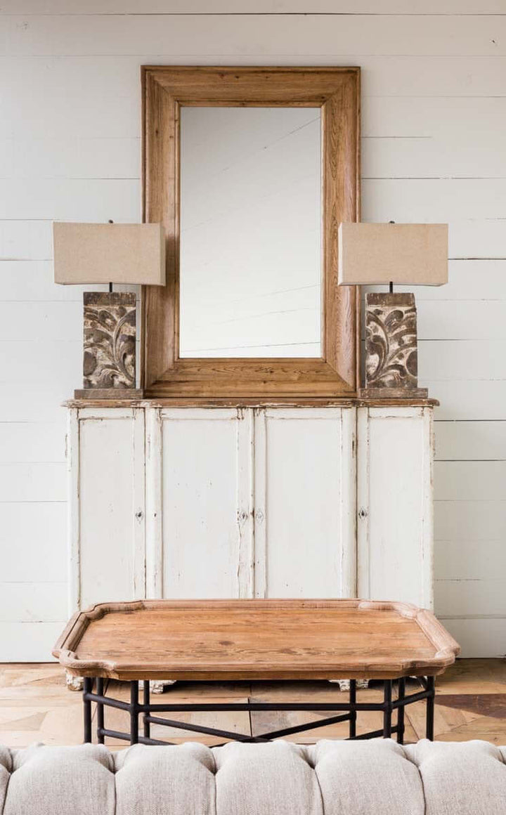 Vintage white painted entryway cabinet with a distressed wood top, featuring rustic lamps and a wooden-framed mirror.