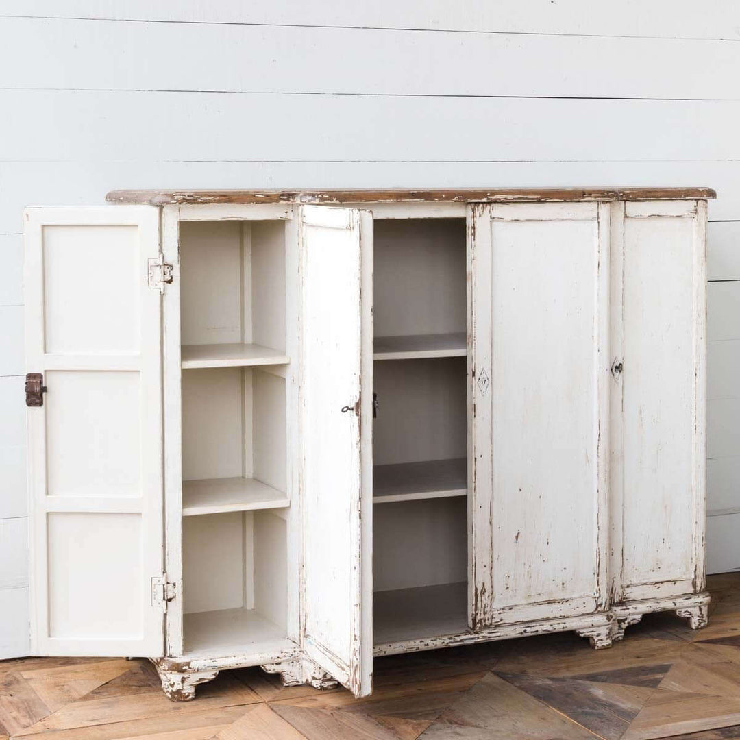Vintage white entryway cabinet with distressed wood top and open doors, showcasing interior shelves against a rustic backdrop.