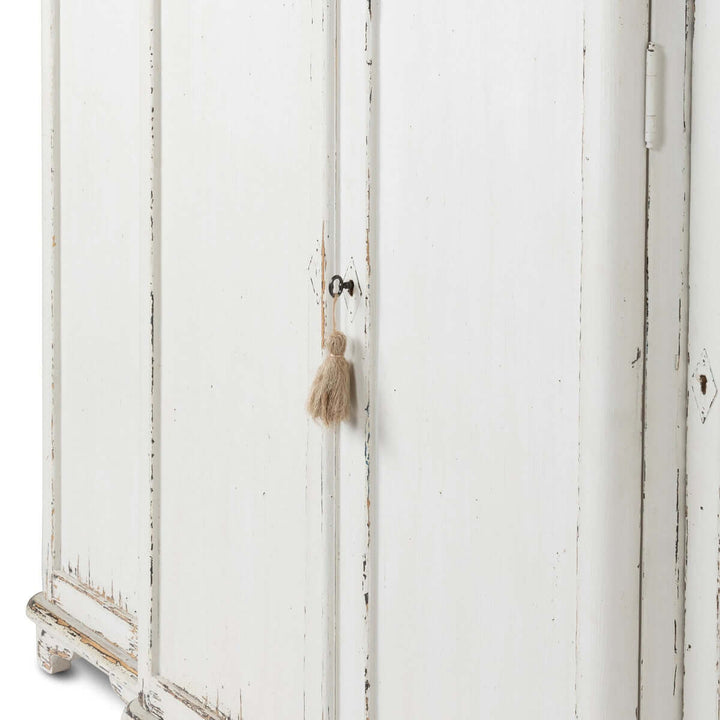 Vintage white painted entryway cabinet with distressed wood top and tassel detail, evoking a cozy, cottage-style ambiance.