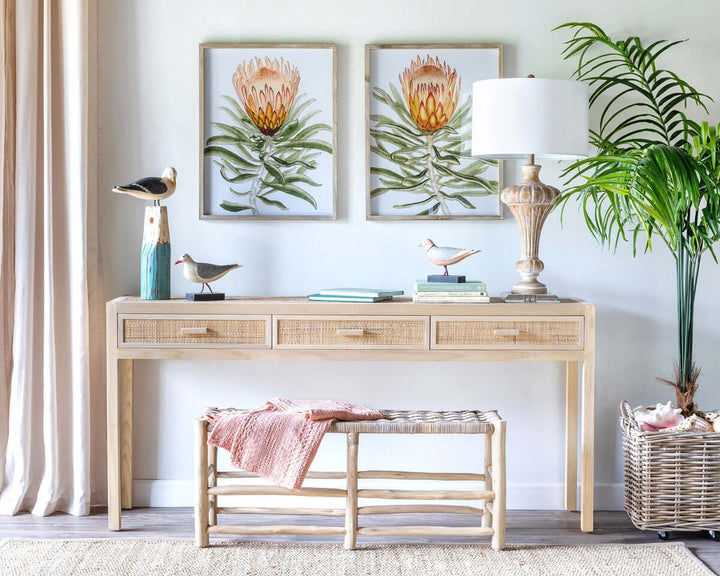 Vintage whitewashed urn table lamp with crystal base and linen shade on wooden console table, accented with coastal decor and wall art.