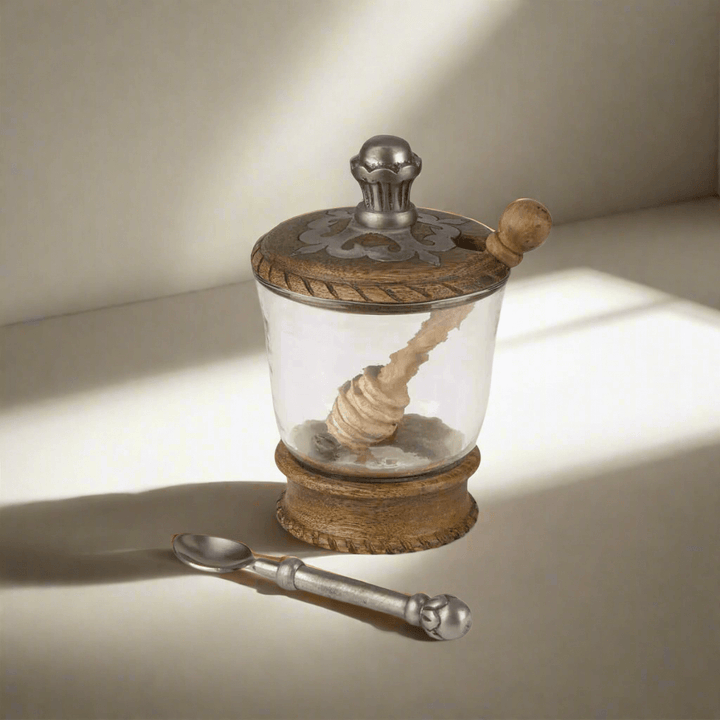 Vintage Wood and Glass Honey Jar with Metal Lid on tabletop with honey dipper and spoon
