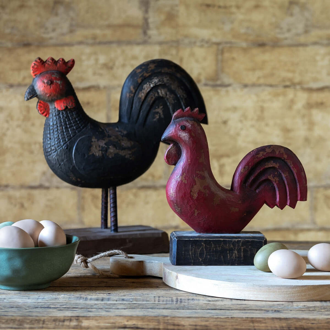 Vintage Wooden Rooster Statue in black and red on rustic table with eggs, showcasing folk art charm in a farmhouse setting.