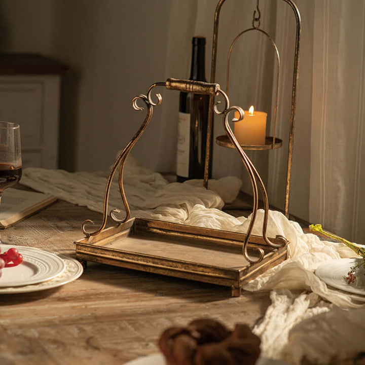 Vintage-inspired antique gold serving tray with ornate scrollwork handles on rustic table.