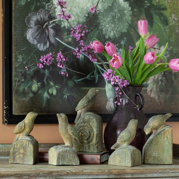 Vintage-inspired bird figurines with aged finish, set of 5, displayed with pink tulips, evoking charm of gardens and verandas.