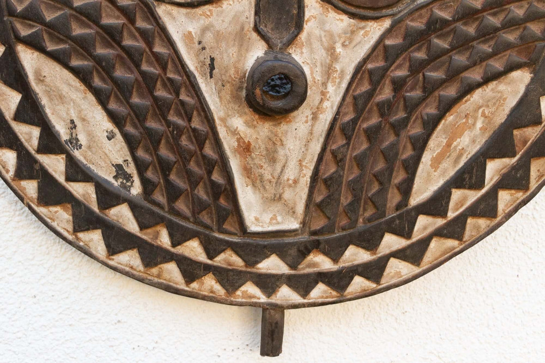 Close-up of hand-carved Vintage Bobo African Sun Mask from Burkina Faso with aged patina and geometric patterns.