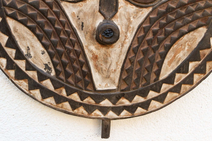 Close-up of hand-carved Vintage Bobo African Sun Mask from Burkina Faso with aged patina and geometric patterns.