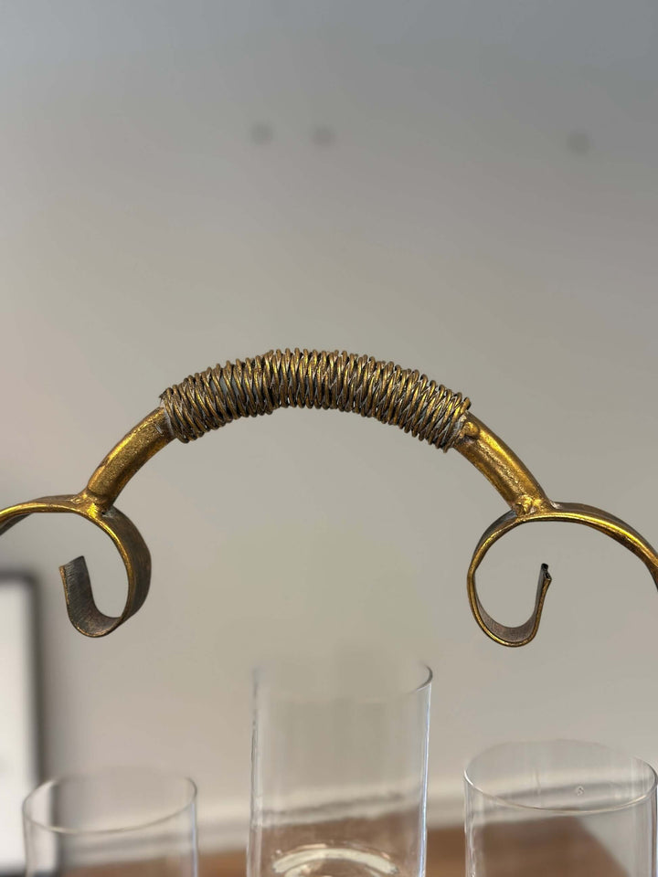Close-up of a vintage brass handle on a 2-tier metal bar cart with ornate detailing, showcasing intricate craftsmanship.