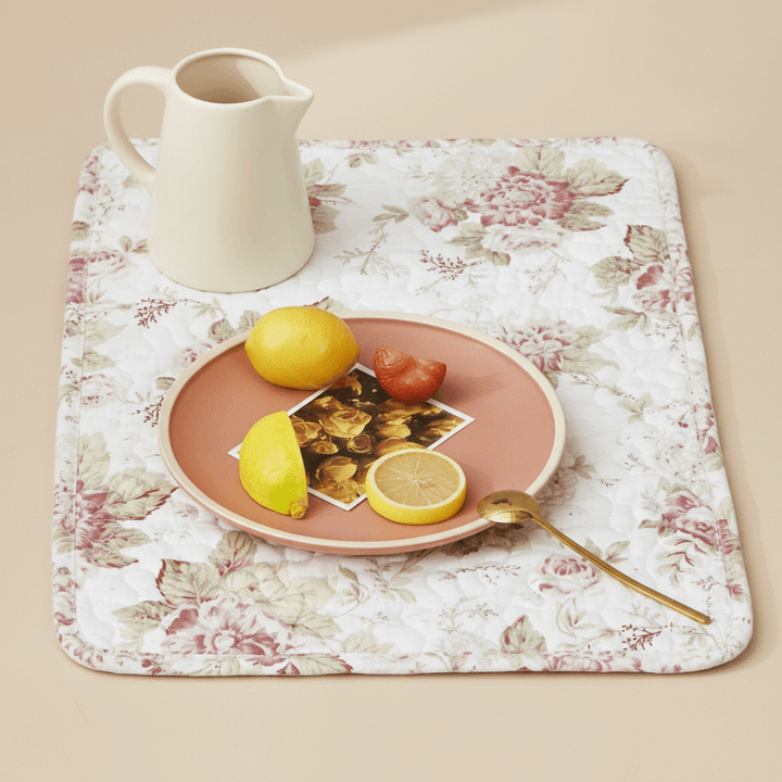 Vintage Cottage Rose Quilted Placemats (Set of 4) with floral design, pitcher, and plate with fruits on a cream background.