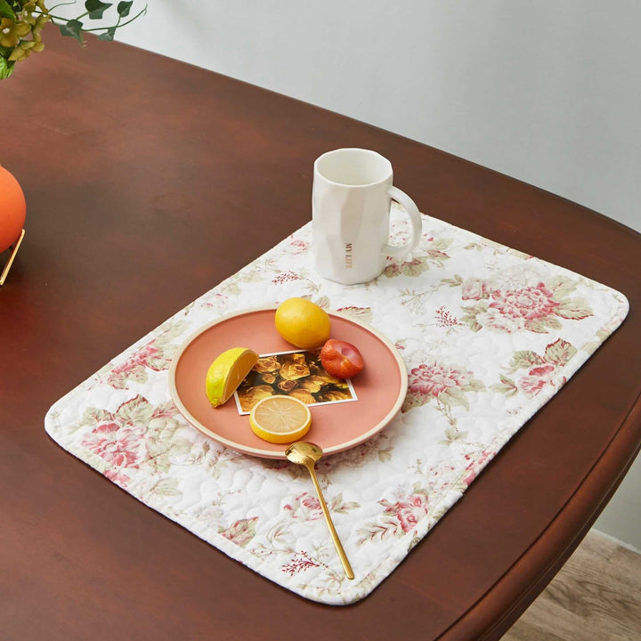Vintage Cottage Rose Quilted Placemats (Set of 4) on a wooden table with a cup and plate