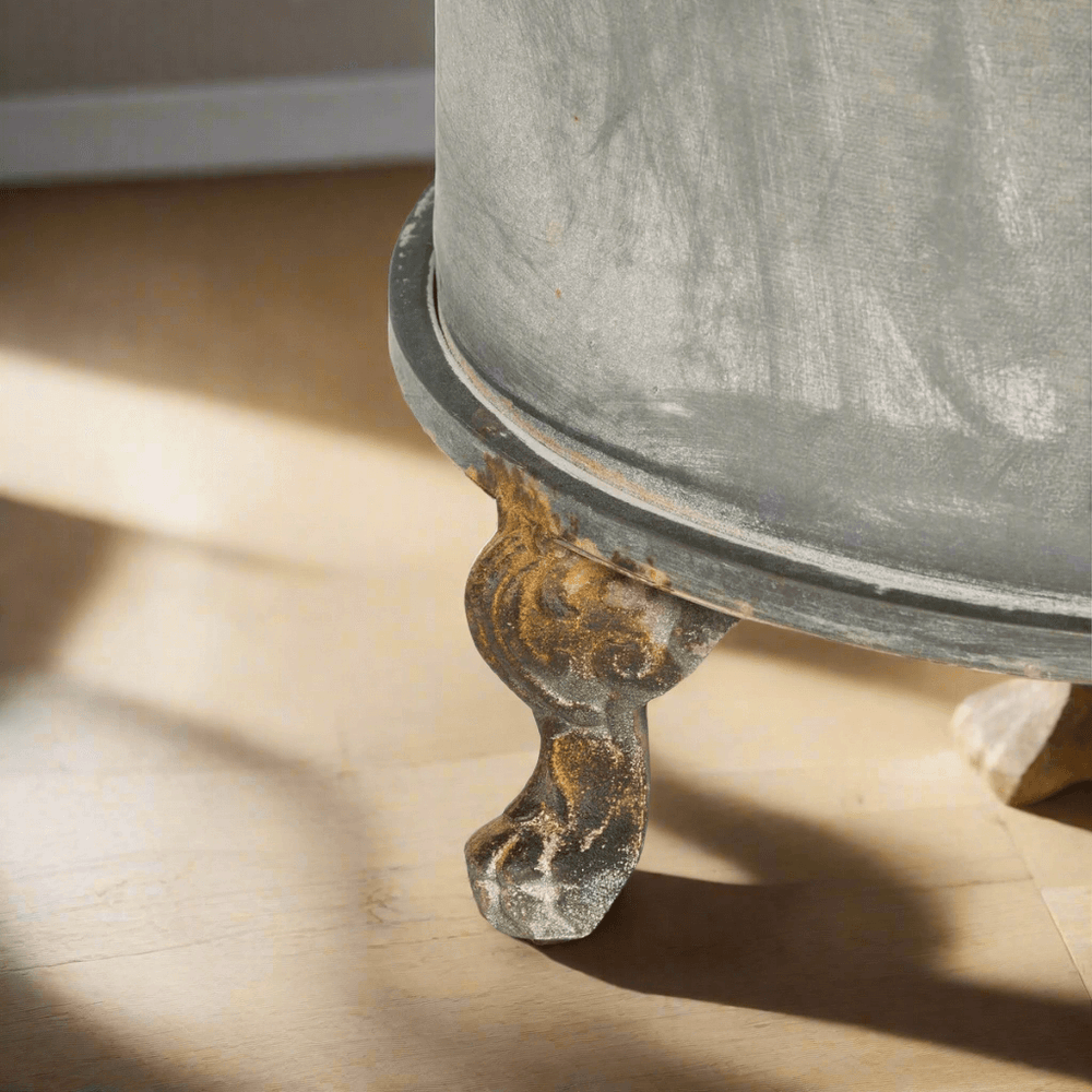 Close-up of the foot of a Vintage Creamery Tank Planter with rustic iron scroll design and warm rust patina, highlighting antique charm.