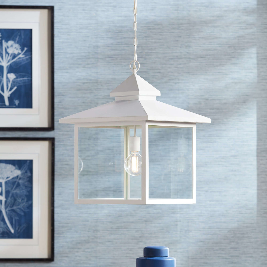 Vintage farmhouse hanging lantern light with clear glass panes, evoking nostalgic charm and craftsmanship in serene setting.