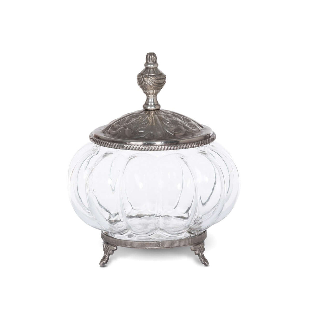 Vintage glass vanity jar with ornate silver lid, pumpkin-shaped body, and decorative feet; evokes Victorian elegance.