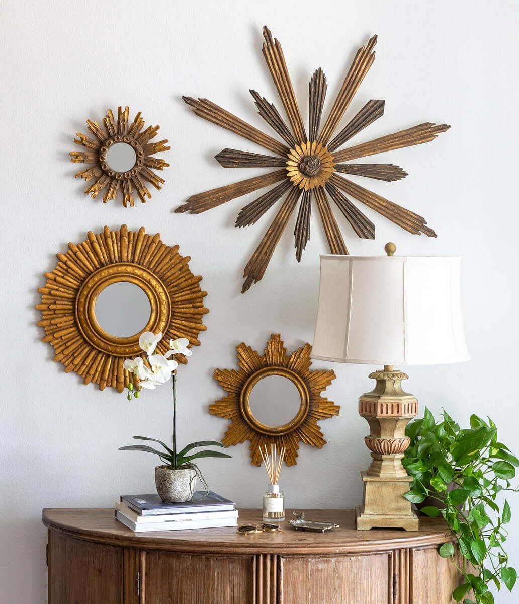 Vintage Greek column table lamp on ornate wooden table with decorative starburst mirrors and plant.