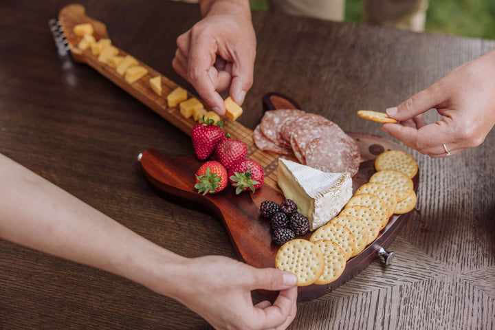 Vintage Guitar-Shaped Cheese Board with Hidden Drawer and Tools on a table with fruit, cheese, and snacks being arranged.