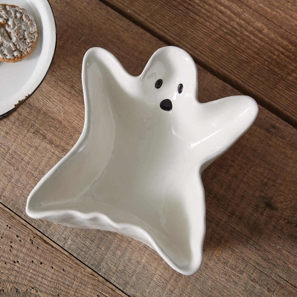 Porcelain candy dish shaped like a ghost, perfect for Halloween decor and serving treats, on a wooden table.