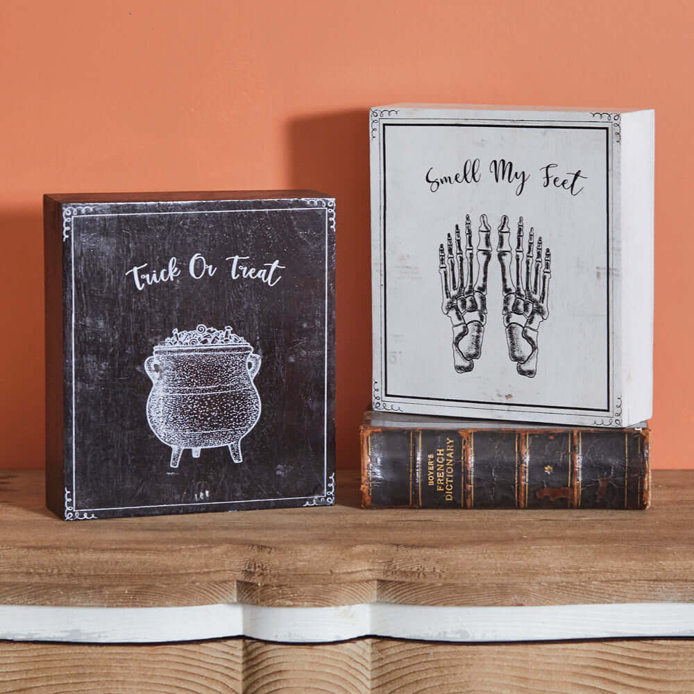Vintage Halloween wood block signs set with 'Trick Or Treat' cauldron and 'Smell My Feet' skeleton design on rustic shelf.