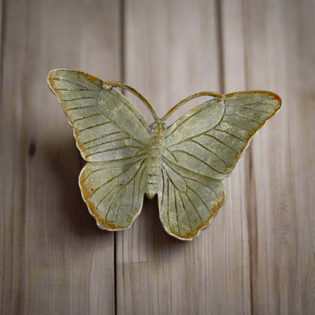 Vintage pewter butterfly trinket dish with antique zinc finish on wood surface, showcases nostalgic charm and delicate design.