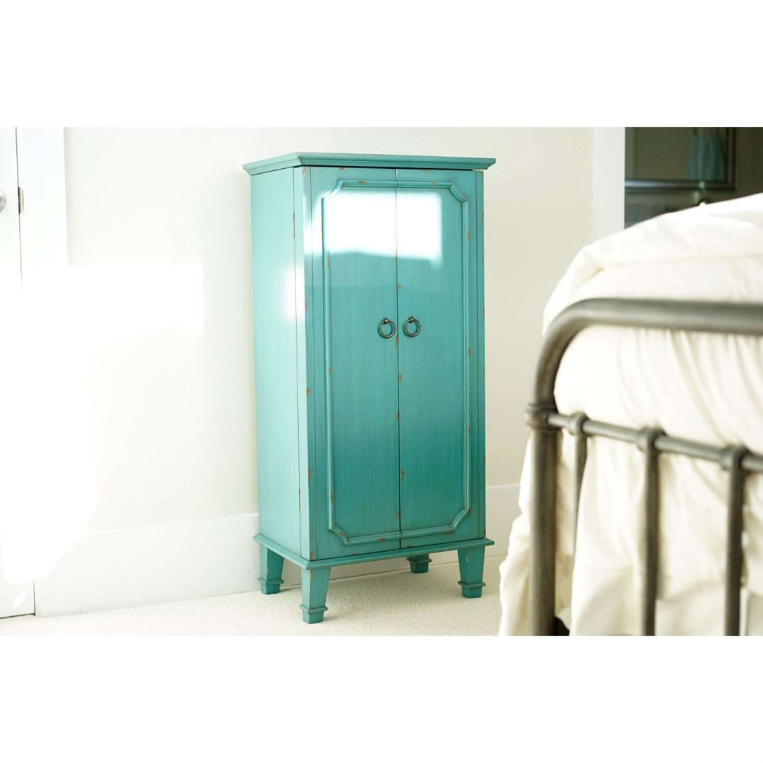 Vintage Turquoise Jewelry Armoire with hand-painted finish and antique hardware in a bedroom setting.