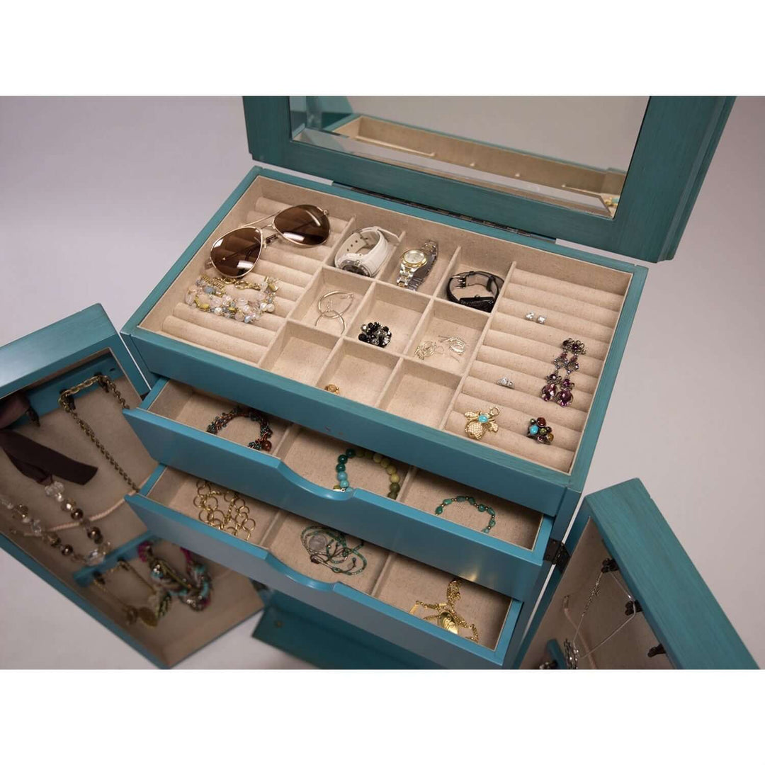 Open drawers of Vintage Turquoise Jewelry Armoire showcasing jewelry storage compartments with necklaces and earrings visible.
