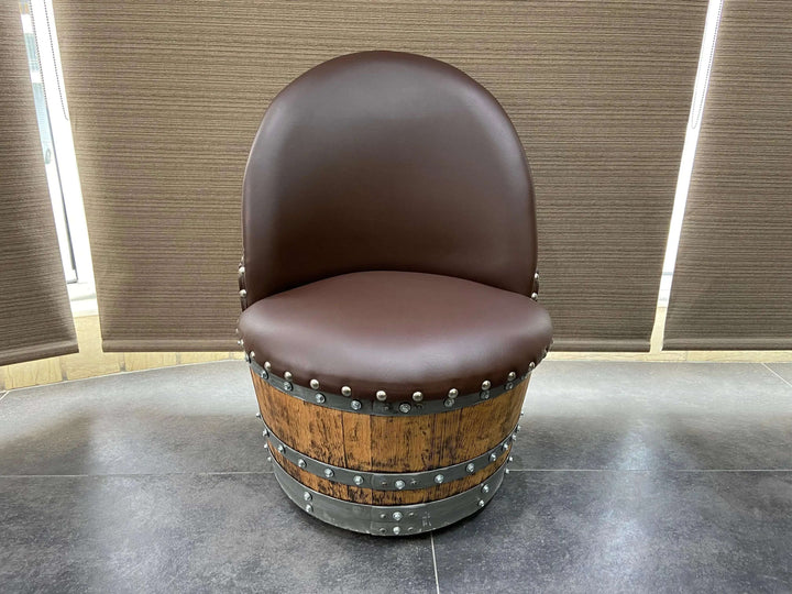 Vintage Whiskey Barrel Chair with brown leather seating on casters, showcasing handcrafted design and hidden compartment feature.