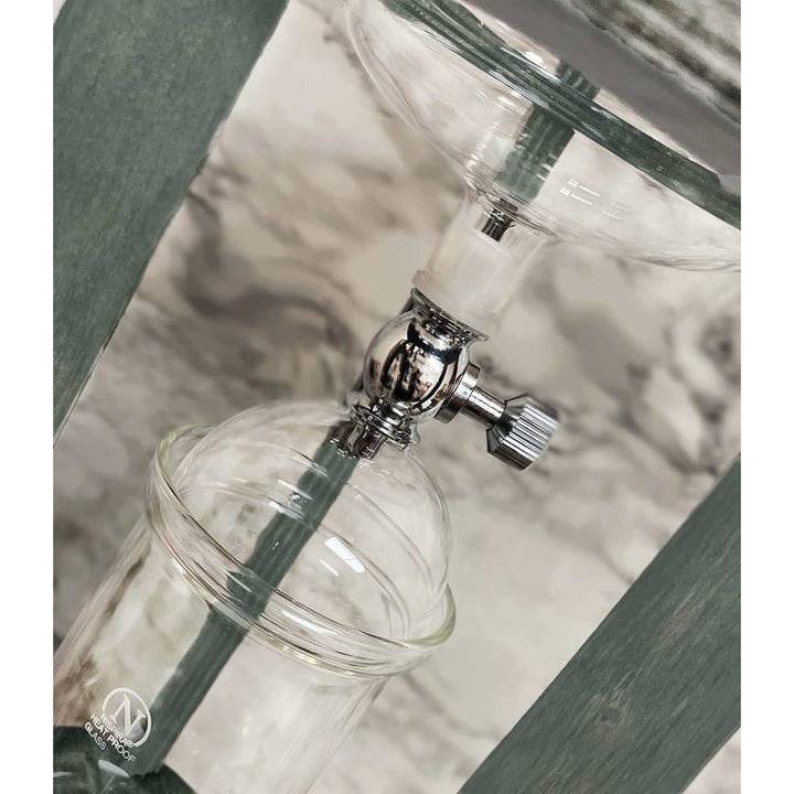Close-up of Vintage Wooden Cold Brew Coffee Maker Tower glass vessels and spout in a rustic kitchen setting.