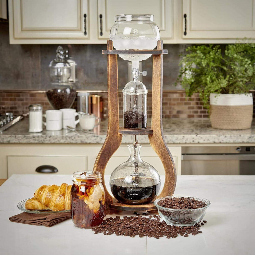 Vintage Wooden Cold Brew Coffee Maker Tower on kitchen counter with croissants and coffee beans.