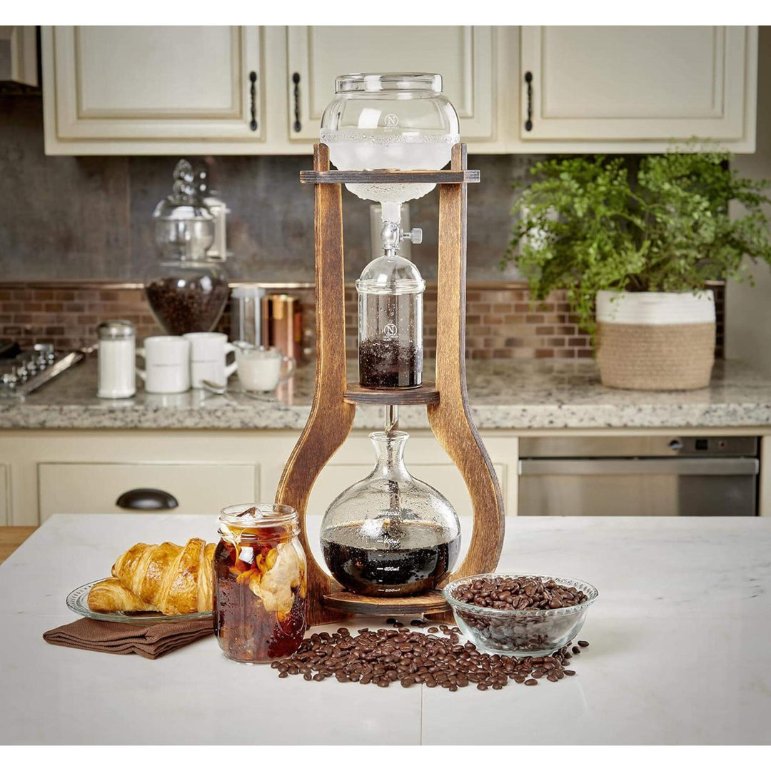 Vintage Wooden Cold Brew Coffee Maker Tower on kitchen counter with croissants and coffee beans.