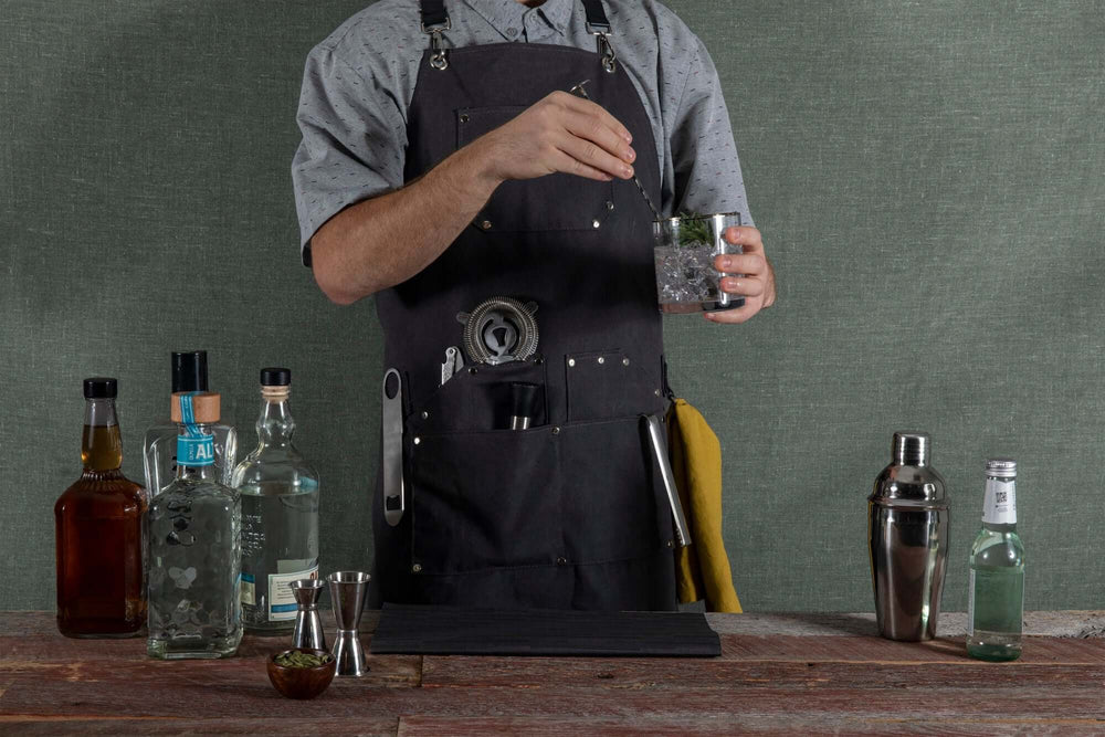 Bartender wearing Waxed Canvas Bartender Apron and Tools while crafting a cocktail, showcasing professional-grade mixology essentials.