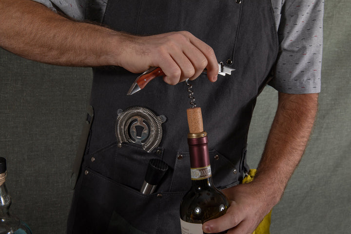 Person using corkscrew wearing Waxed Canvas Bartender Apron and Tools