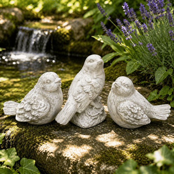 Three Weathered Cement Bird Garden Statues beside a garden pond