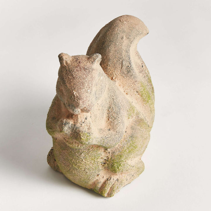 Weathered moss terracotta squirrel garden statue, adding a whimsical touch to outdoor spaces.
