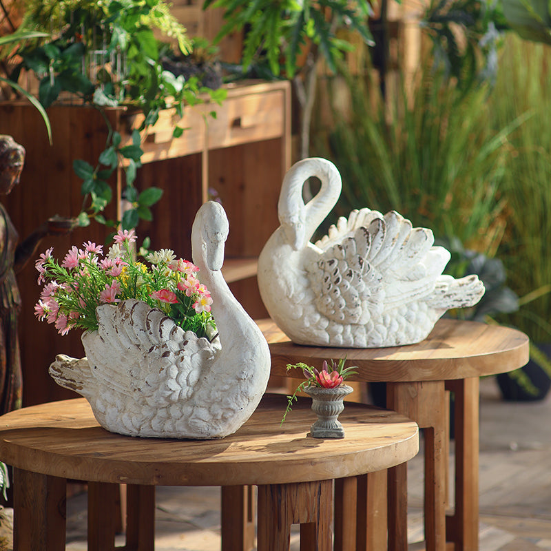 Weathered Swan Garden Planters filled with pink flowers on wood tables