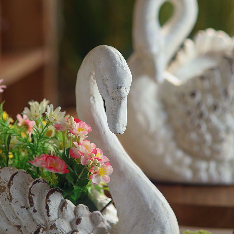 Close view of the softly distressed swan neck and flower-filled planter