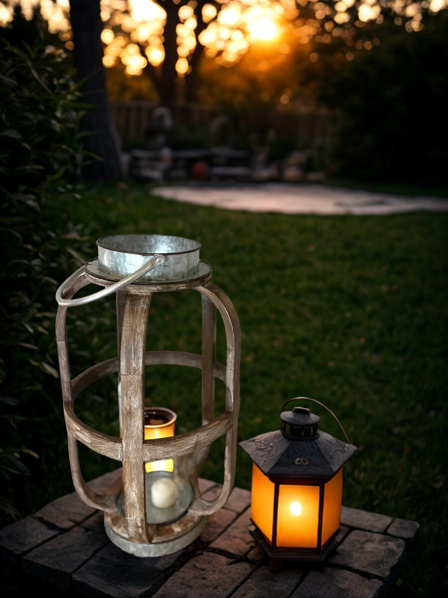 Rustic wood and metal lantern glowing outdoors beside a smaller candle lantern