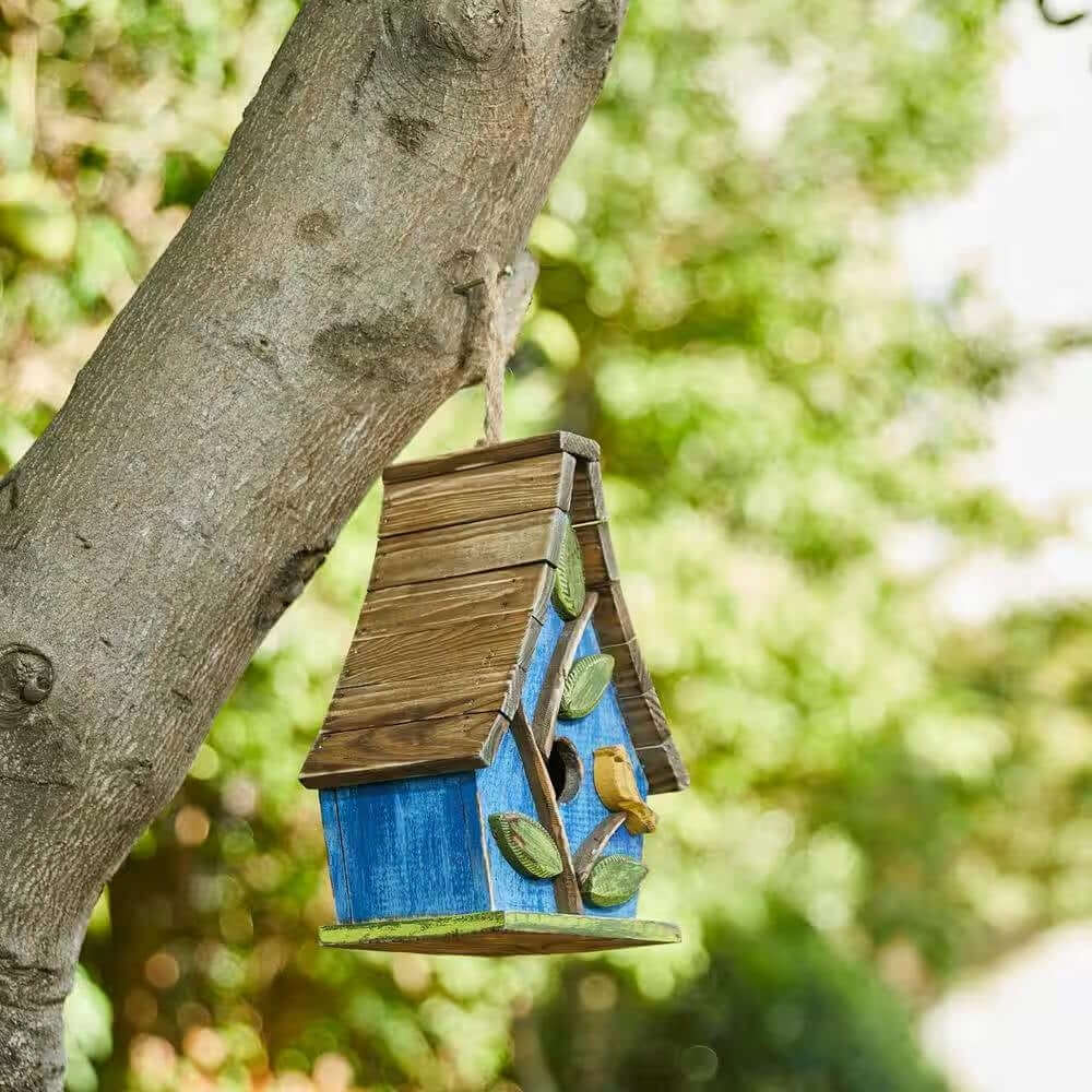 Handcrafted Whimsical Cottagecore Blue Wood Birdhouse hanging on tree, featuring distressed finish, green leaves, and yellow bird detail.
