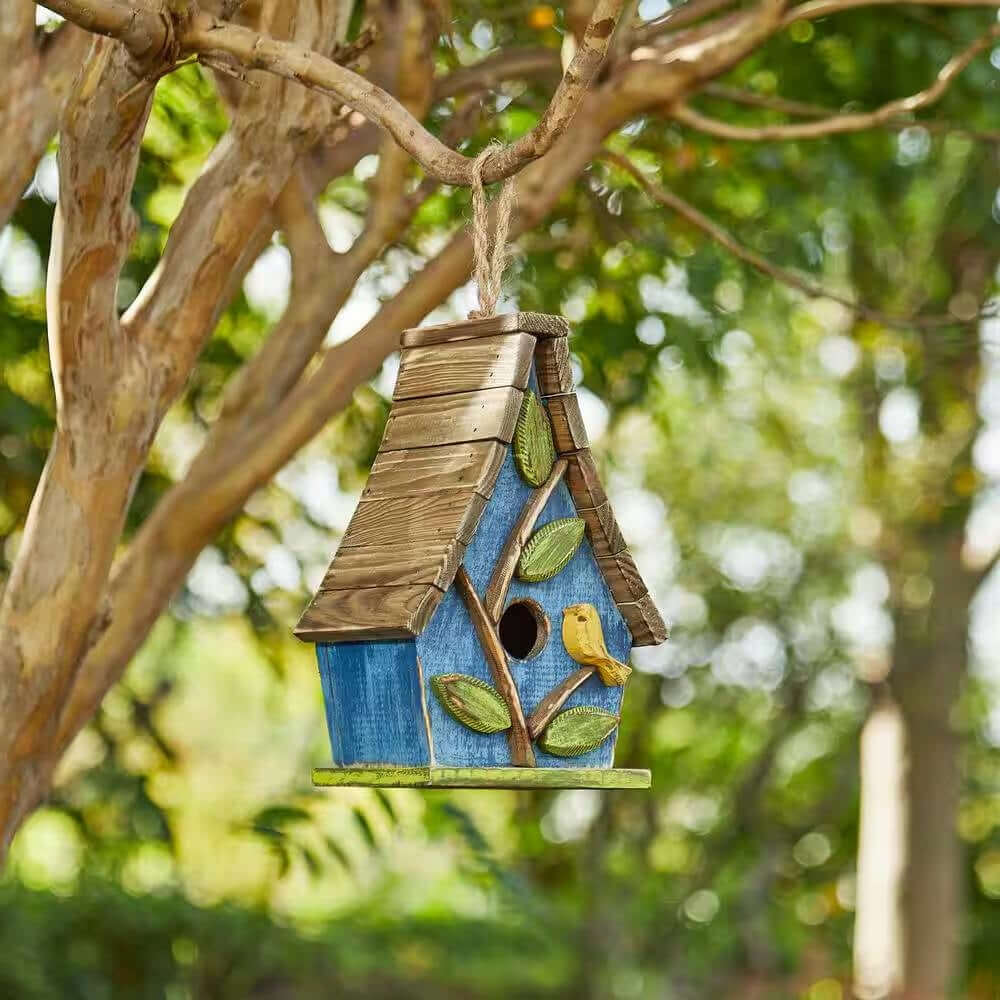 Whimsical Cottagecore Blue Wood Birdhouse hanging in a tree with green leaves and perched yellow bird, creating a fairytale garden vibe.