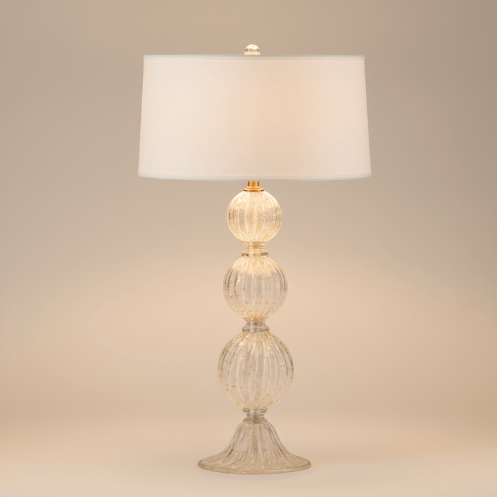 Decorative table lamp with glass base and white shade on a beige background