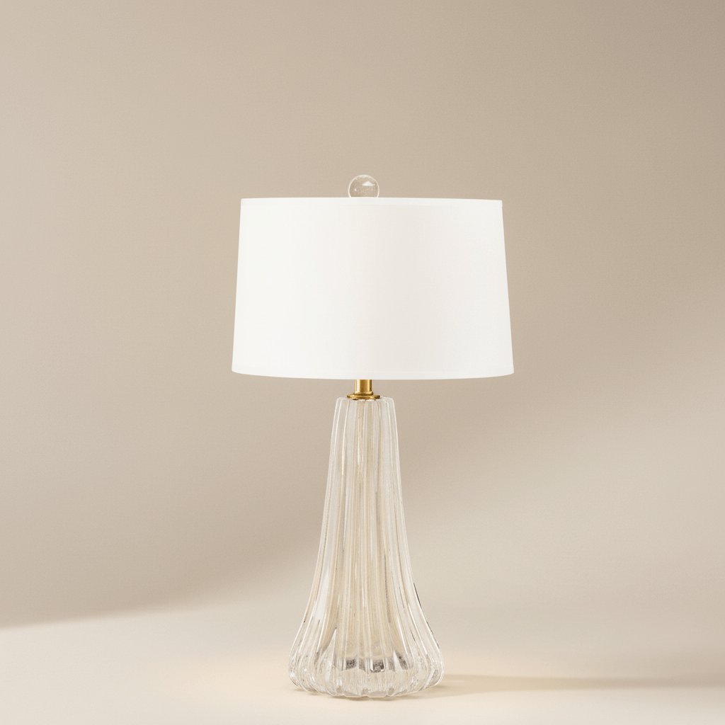 Table lamp with a white shade and ribbed glass base on a beige background