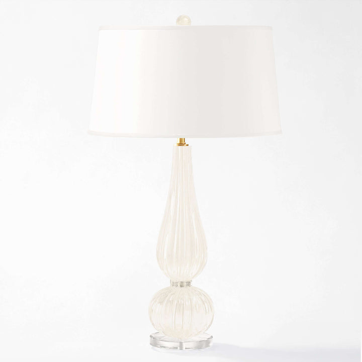 Decorative table lamp with a white shade and ribbed glass base on a white background
